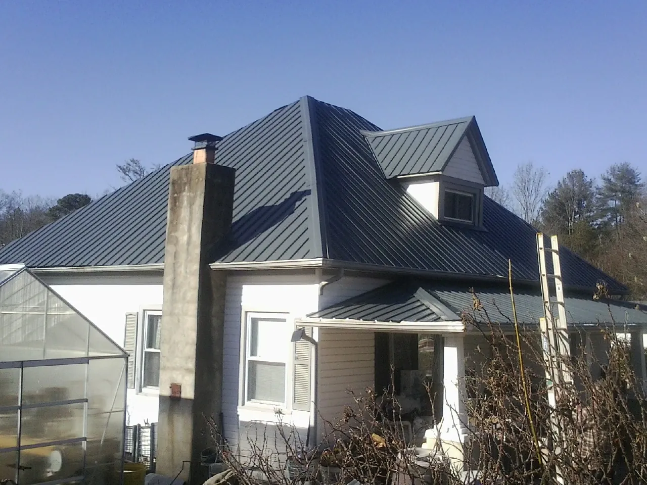 Dark blue standing seam metal roof on a white farmhouse with dormer — Slate & Tile Roof Repair by Roofing Brothers in Mayo