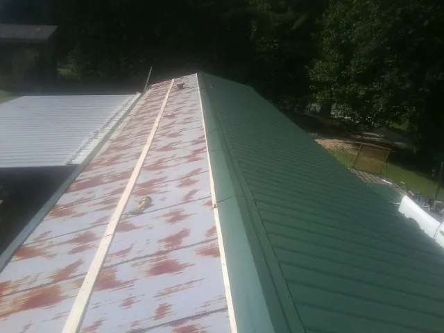 Old rusted panels beside newly installed green metal roofing — Wind Damage Roof Repair by Roofing Brothers in Mayo