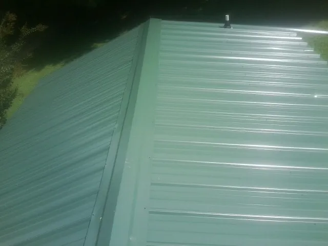 New green metal panels meeting at the ridge of a roof — Flat Roof Repair work by our crew in Mayo