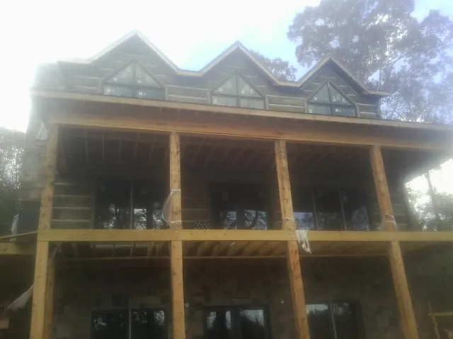 Dormers and porch framing on a large log home under construction — Roof Coating work by our crew in Mayo