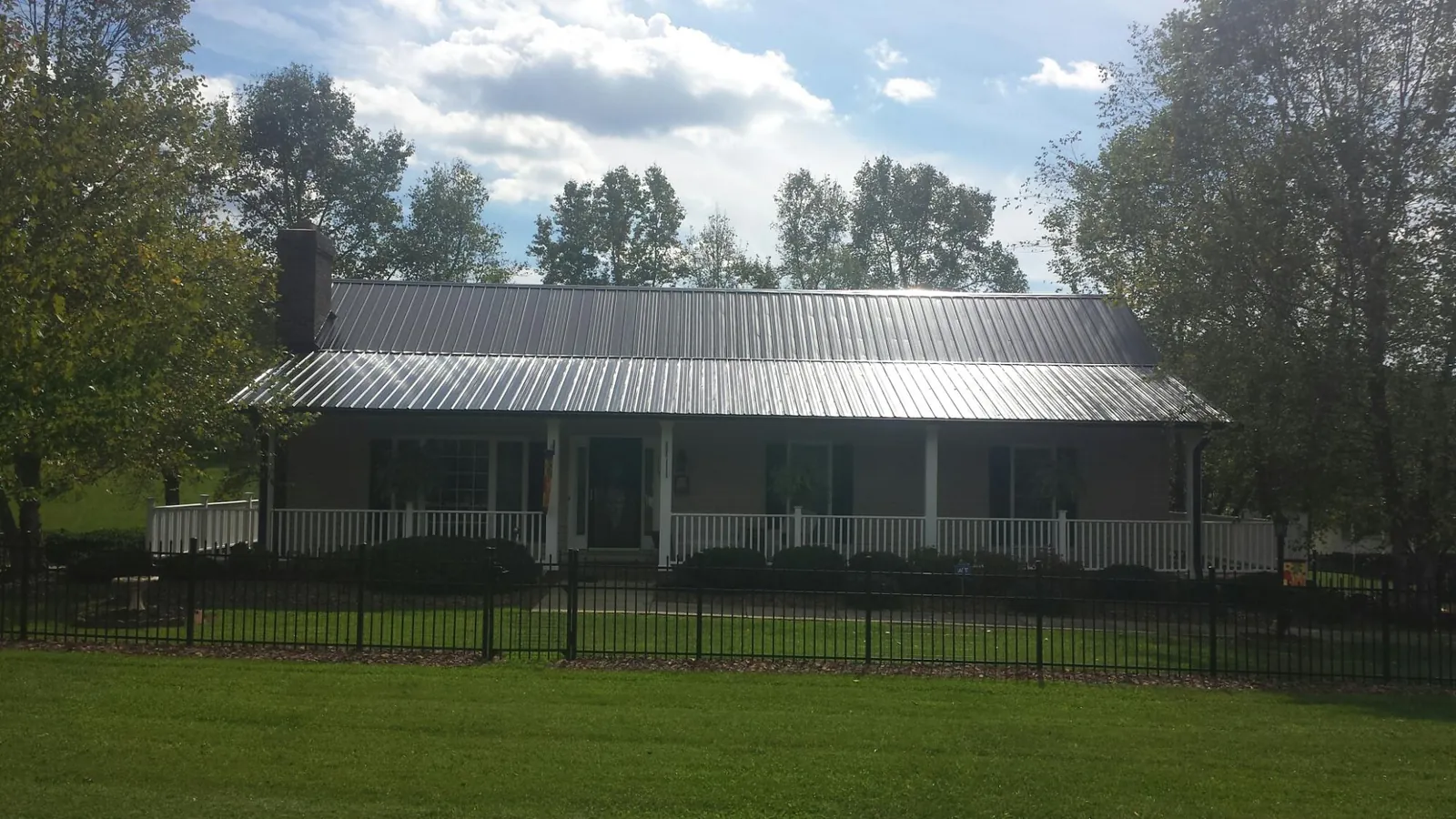 Gray metal roof on a brick ranch with a full width front porch — Gutter Guard Installation work by our crew in Mayo