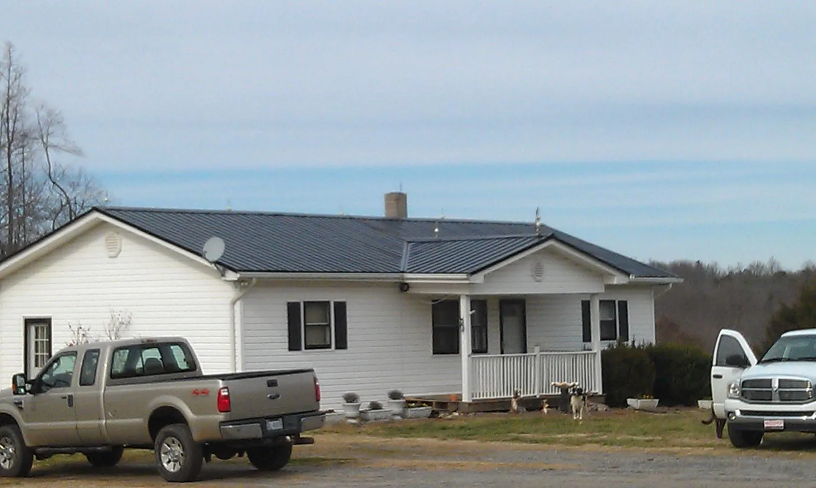 Finished dark metal roof on a white ranch home with work trucks parked in Mayo